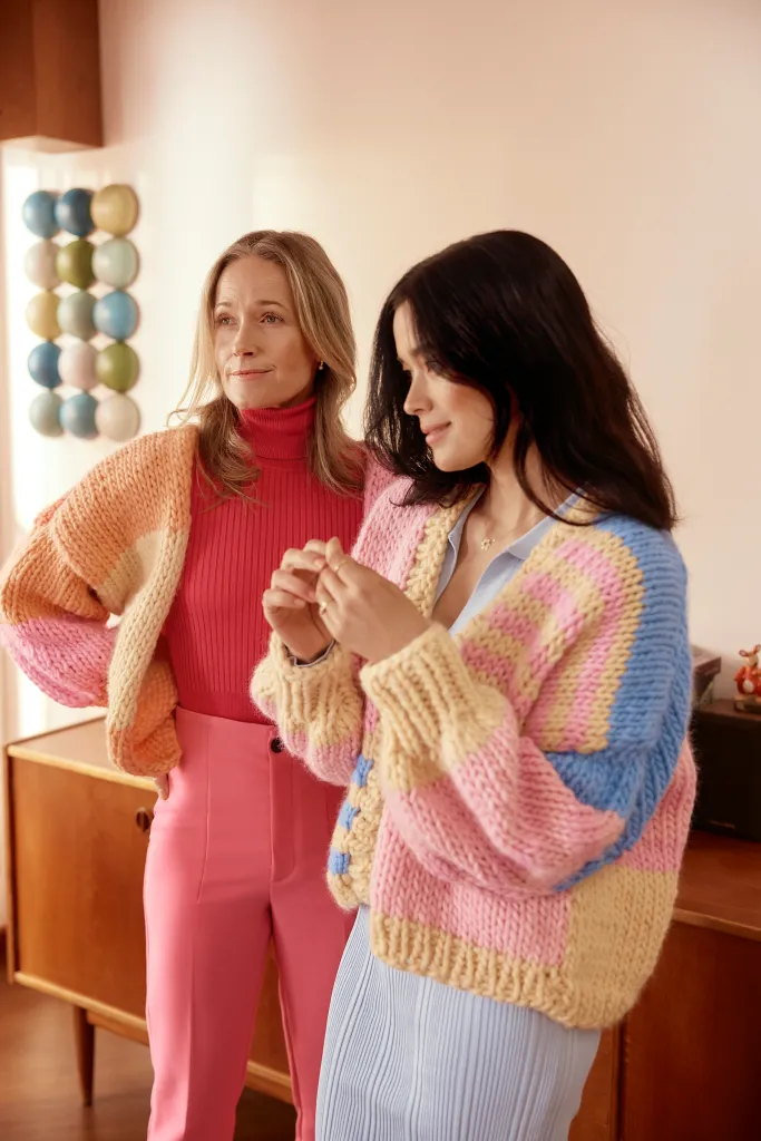 Two women in colourful, pastel knit jumpers.